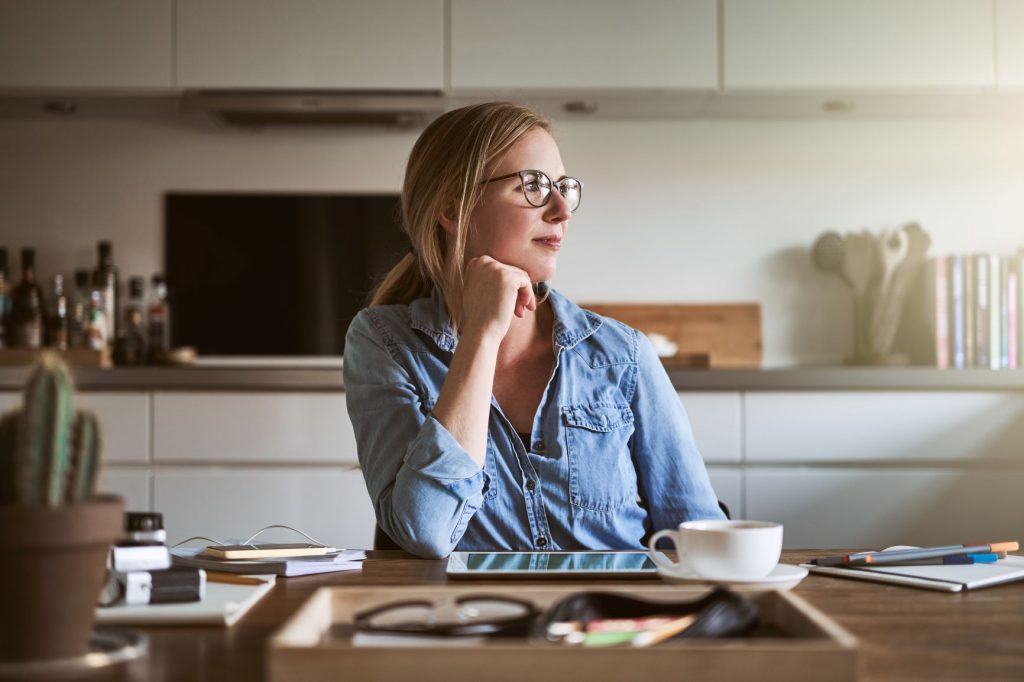 Woman sitting at a kitchen table thinking