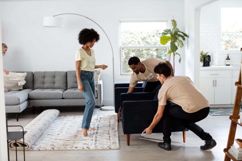two men placing an armchair while a woman supervises