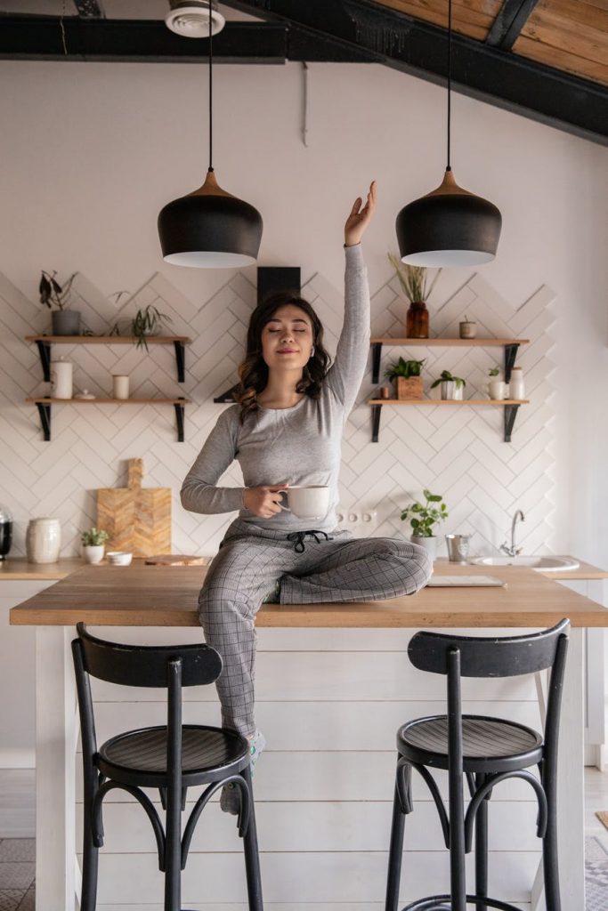 ethnic woman sitting with cup of hot drink on table