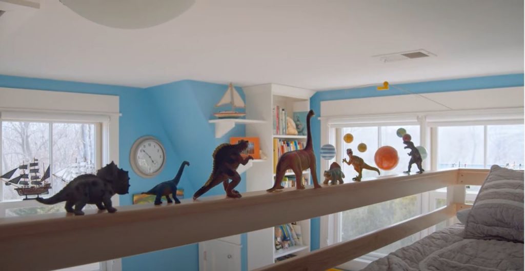 dinosaurs lined up on the ledge of a bunk bed