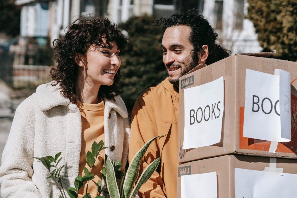 couple moving out carrying boxes and plants