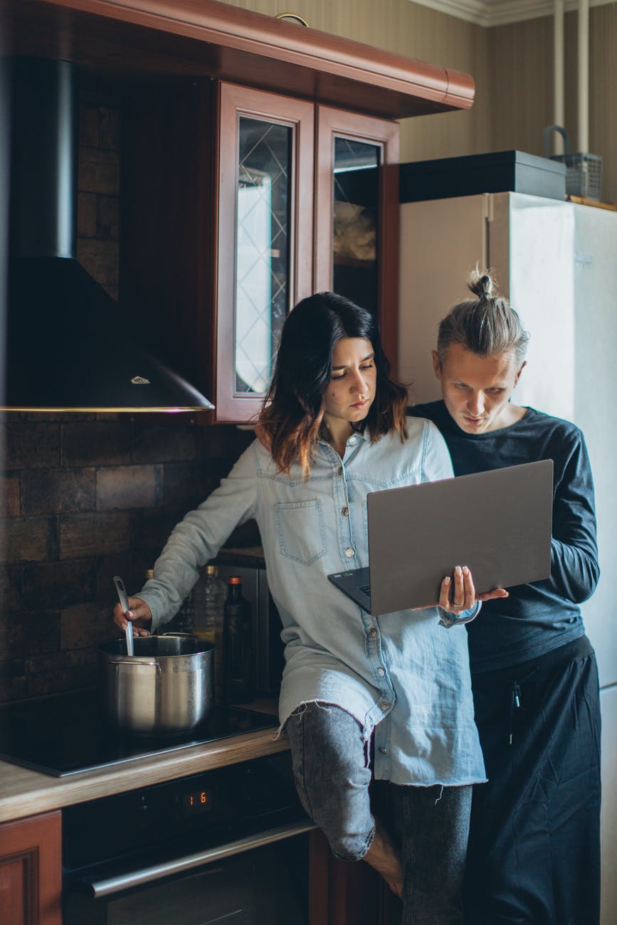 woman cooking while holding her laptop