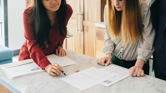 A real estate agent shows a home buyer a contract
