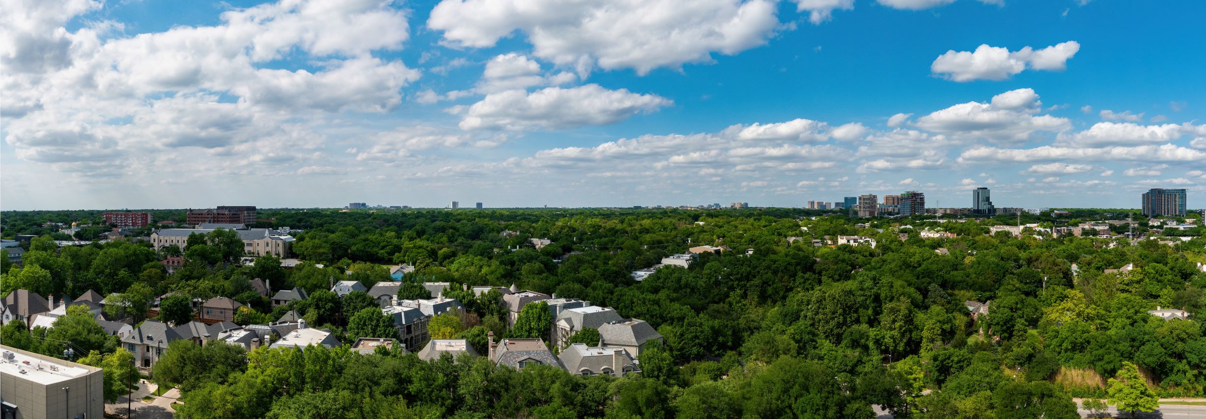 Far view of Dallas skyline with trees and a neighborhood in the foreground