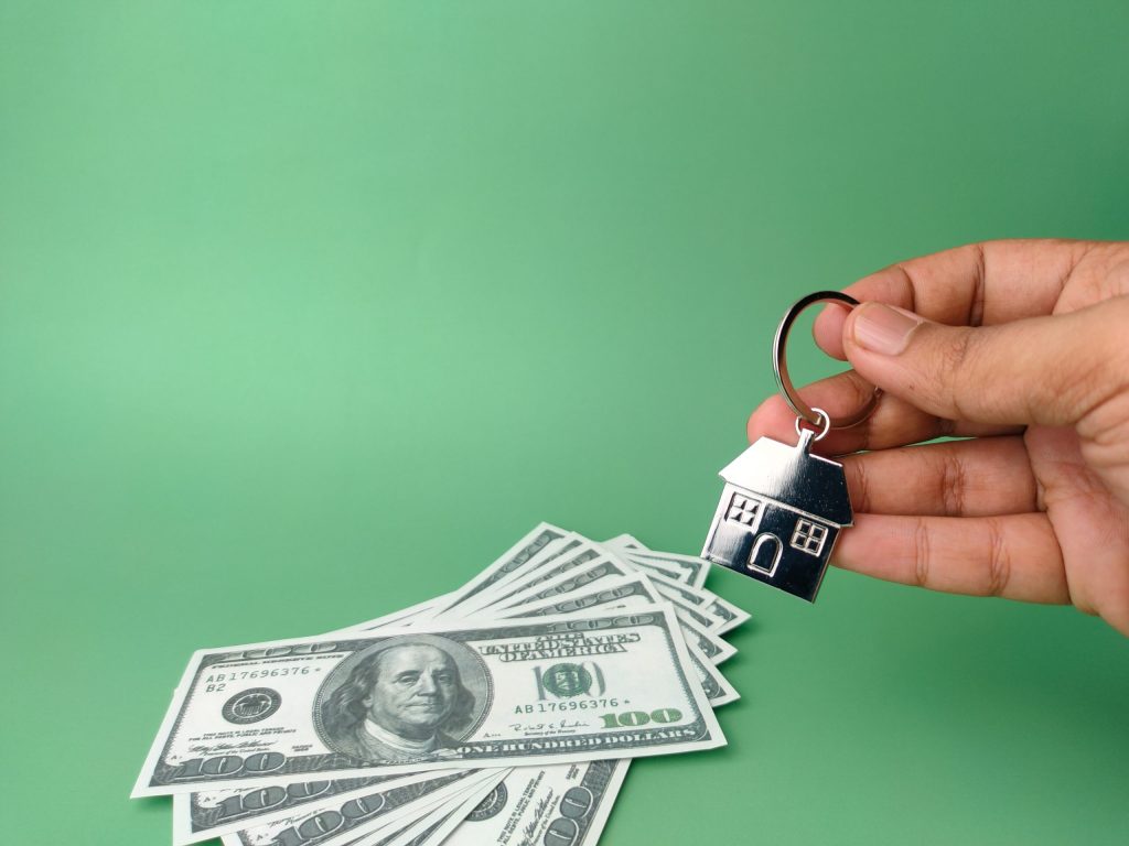 Hand holding house keychain and banknotes
