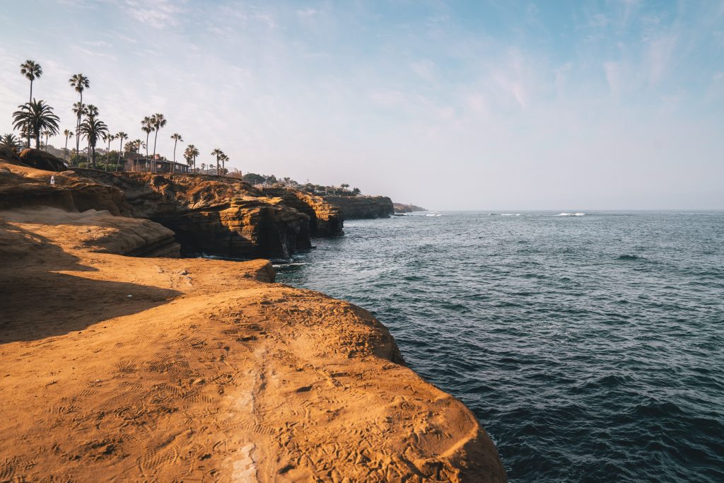 people on brown rock formation near body of water during daytime
